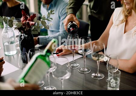 Beschnittenes Bild von Geschäftsmann, der Rotwein im Glas ausgießt kongresszentrum Stockfoto
