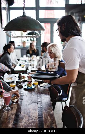 Kellner serviert den Gästen Dessert auf dem Esstisch Stockfoto