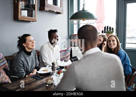 Glückliche männliche und weibliche Freunde genießen im Restaurant Stockfoto