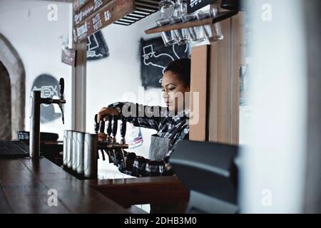 Weibliche Barkeeperin gießt Bier vom Fass im Restaurant Stockfoto