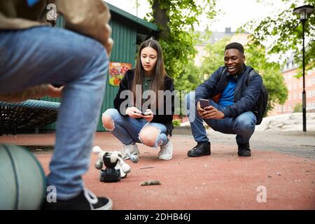 Freunde steuern Roboter mit Smartphone, während mit Kampf an parken Stockfoto