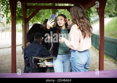 Teenager-Mädchen Anwendung Make-up auf weibliche Freundin unter Selfie Stockfoto