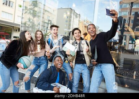 Fröhliche Teenager-Mädchen, die Selfie mit Freunden auf dem Weg durch Store in der Stadt Stockfoto