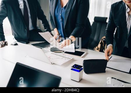 Mittelteil der Geschäftsfrau, die Dokumente nach Tabelle mit Kollegen in hält Konferenzraum Stockfoto