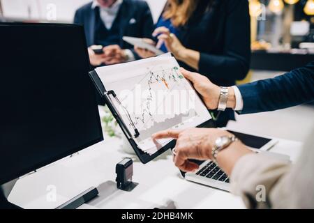 Zugeschnittenes Bild von Geschäftspartnern, die Graph im Besprechungsraum analysieren Im Büro Stockfoto