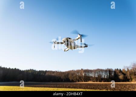 Nahaufnahme eines DJI Quadcopter Drone Mavic mini 249g. Drohne, die vor Sonnengrund fliegt. Stockfoto