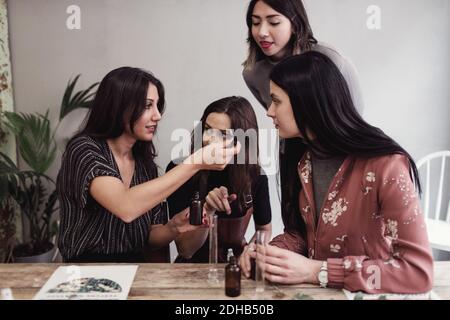 Junge Frau, die im Workshop weiblichen Kollegen die Parfümpipette zeigt Stockfoto