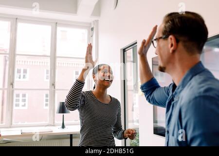Glückliche Geschäftsfrau geben High-Five zu männlichen Kollegen im Büro Stockfoto