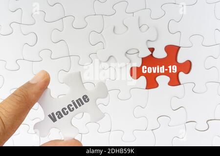 Hand halten Puzzle mit Text IMPFSTOFF und COVID-19. Covid-19 und Coronavirus-Konzept Stockfoto