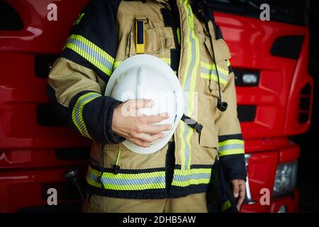 Mittelteil der weiblichen Feuerwehrfrau mit Helm, während sie in Brand steht Station Stockfoto