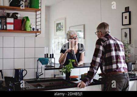 Rentnerehepaar, das an der Küchentike steht und über digitale Medien diskutiert Tablet Stockfoto