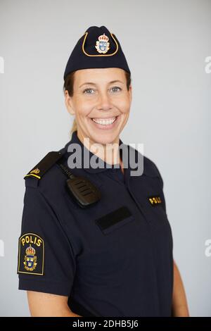 Porträt einer lächelnden Polizistin in Uniform, die vor weißem Hintergrund steht Stockfoto