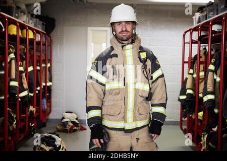 Portrait von selbstbewussten männlichen Feuerwehrmann tragen Schutzuniform stehend in Umkleideraum an der Feuerwehr Stockfoto