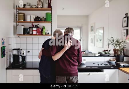 Rückansicht des Rentnerpaares, das in der Küche steht Zu Hause Stockfoto