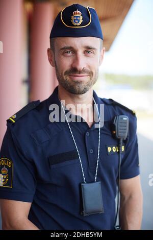 Porträt eines lächelnden Polizisten in Uniform, der vor der Polizeistation steht Stockfoto