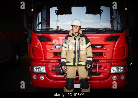 Porträt einer Feuerwehrfrau, die vor dem Feuerwehrmann steht An der Feuerwehr Stockfoto