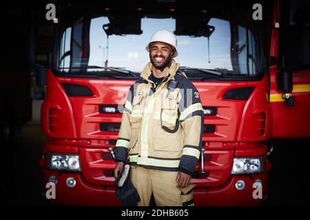 Porträt eines lächelnden Feuerwehrmann in Uniform, der gegen den Feuerwehrmann steht An der Feuerwehr Stockfoto