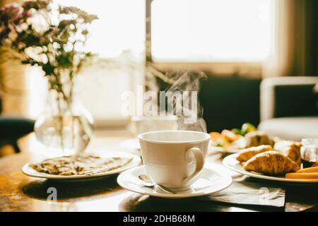 Heißer Kaffee mit Mahlzeit serviert im Frühstück auf dem Tisch Hotelzimmer Stockfoto
