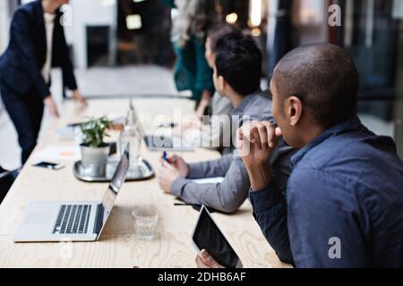 Kollegen aus dem Unternehmen hören zu, während sie während des Meetings am Tisch sitzen Stockfoto