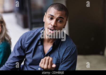 Junger Geschäftsmann gestikuliert, während im Büro sprechen Stockfoto