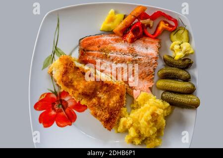 Gebratener Fisch auf dem Feuer und im Ofen, Kartoffelpüree und eingelegte Gurken Stockfoto