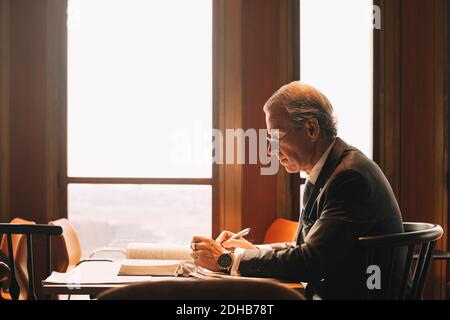 Seitenansicht der reifen Anwalt Recherche beim Lesen von Büchern an Büro Stockfoto