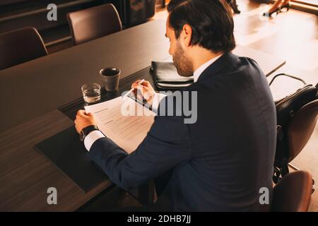 Ansicht eines männlichen Anwalts, der Dokumente am Tisch überprüft In der Anwaltskanzlei Stockfoto