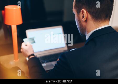 High-Angle-Ansicht des Geschäftsmannes mit Kreditkarte während der Verwendung Laptop am Flughafen Stockfoto