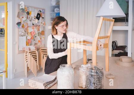 Junge Polsterarbeiterin, die in der Werkstatt am Stuhl arbeitet Stockfoto