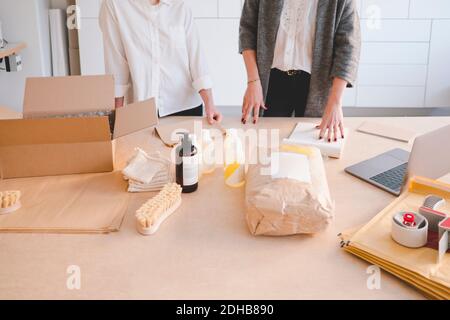 Mittelteil von Unternehmerinnen stehen mit verschiedenen Fertigungs-Objekte auf Tabelle in der Werkstatt Stockfoto