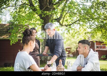 Lächelnder Besitzer, der Kellnerin beibringt, während Gäste am Tisch sitzen Restaurant Stockfoto