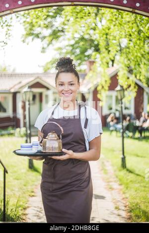 Porträt einer lächelnden Kellnerin, die das Serviertablett im Restaurant hält Stockfoto