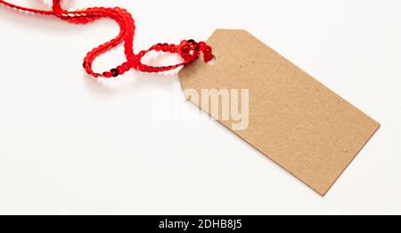 Blank brauner Karton Geschenkanhänger, Karton Papier Etikett isoliert auf weißem Hintergrund. Kraft recyceln Preiskarte mit rotem glänzenden Band, Schablone, Kopierraum Stockfoto