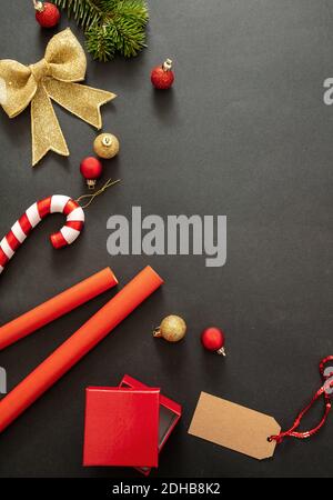 Weihnachtsgeschenke Vorbereitung. Geschenkschachteln Verpackung auf schwarzem Hintergrund, Draufsicht. Rote Farbverzierungen und Zubehör, Kartenschablone, Kopierraum Stockfoto
