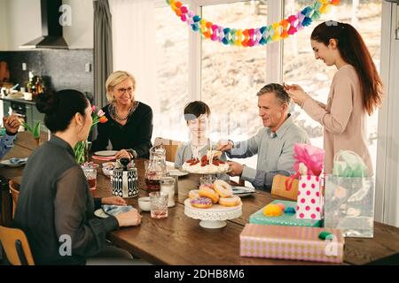Multi-Generation-Familie genießen Geburtstagskuchen am Tisch während der Party Stockfoto