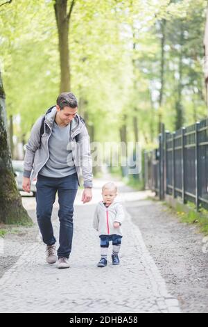 Voller lächelnder Vater, der den Sohn beim Gehen ansieht Fußweg Stockfoto