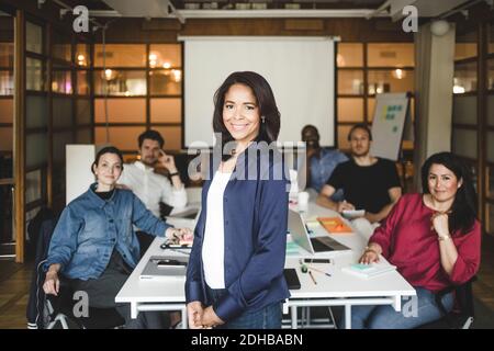 Porträt einer selbstbewussten Managerin, die mit dem Team im Hintergrund steht Im Büro Stockfoto