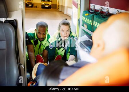 Multiethnische Sanitäter ziehen den Patienten zusammen aus dem Krankenwagen Stockfoto