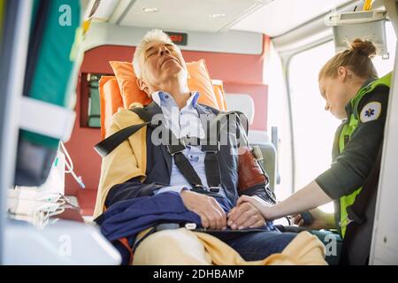 Weibliche Sanitäterin, die den Blutdruck des Mannes im Krankenwagen überprüft Stockfoto