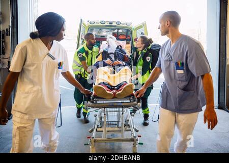 Mitarbeiter im Gesundheitswesen, die den Patienten im Krankenhaus auf die Liege schieben Stockfoto