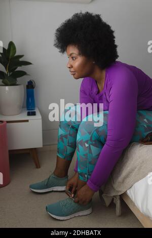 afroamerikanische Frau, die Sportkleidung im Schlafzimmer anlegt. Selbstisolation zu Hause während der Coronavirus covid 19 Pandemie. Stockfoto