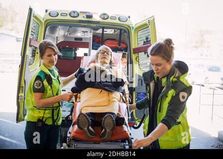 Weibliche Sanitäter, die den Patienten auf einer Krankenliege herunterziehen Stockfoto