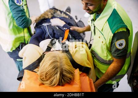 Weitwinkelansicht eines männlichen Sanitäters, der eine Patientin anschaut Auf der Krankenliege Stockfoto