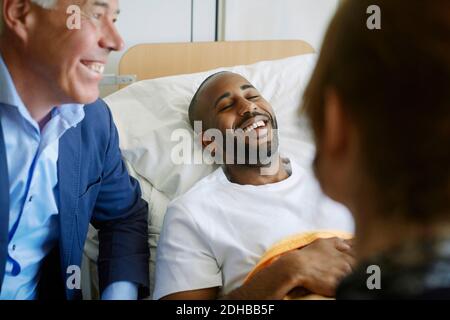 Lächelnder junger Patient mit geschlossenen Augen auf dem Bett liegend Krankenhausstation Stockfoto