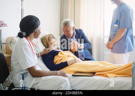 Gesundheitshelfer, die einen älteren Mann betrachten, der den Patienten im Krankenhaus tröstet Station Stockfoto