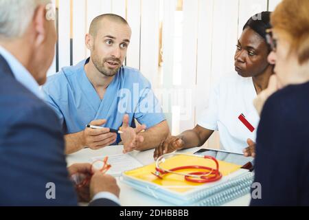 Männliche und weibliche Ärzte diskutieren mit Mann und Frau während Besuch in der Klinik Stockfoto