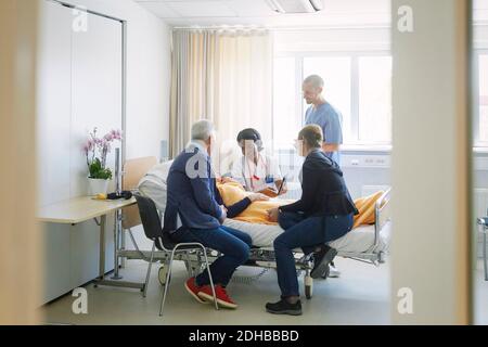 Medizinische Fachkräfte diskutieren mit der Patientin und ihren Freunden auf der Station Im Krankenhaus Stockfoto