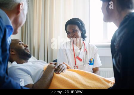 Lächelnde Ärztin im Gespräch mit Patienten und Familie im Krankenhaus Station Stockfoto