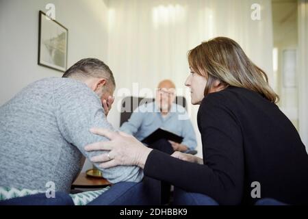 Frau tröstet Mann während Beratung Sitzung mit Therapeuten Stockfoto