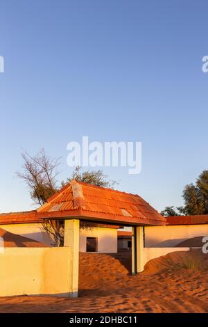 Mauer und gefliestes Tor in Sanddünen in der Wüste in Al Madam Geisterdorf, Vereinigte Arabische Emirate, Sonnenuntergang, Kopierraum begraben. Stockfoto